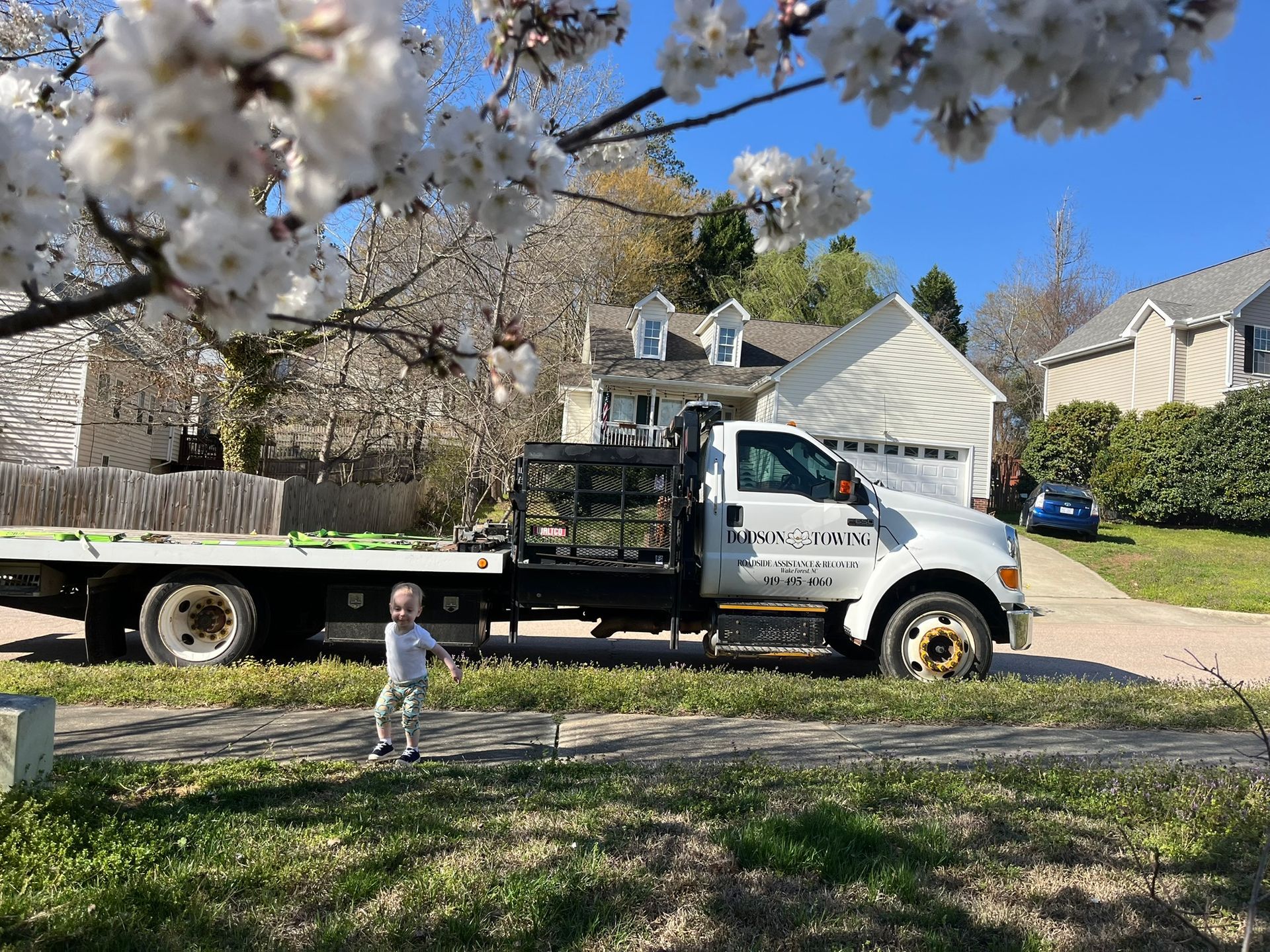 A little boy is standing in front of a tow truck.