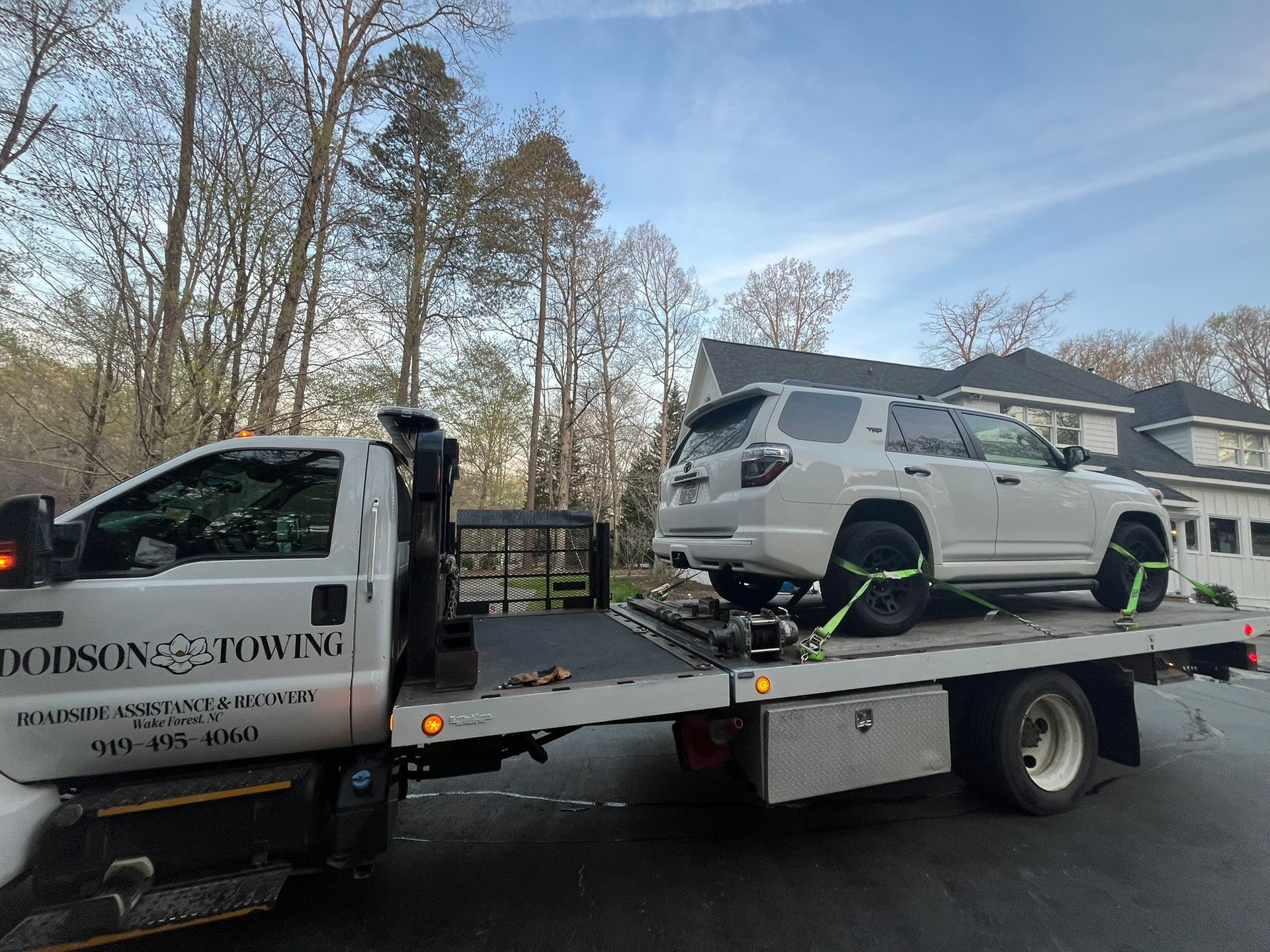 A white suv is being towed by a tow truck.