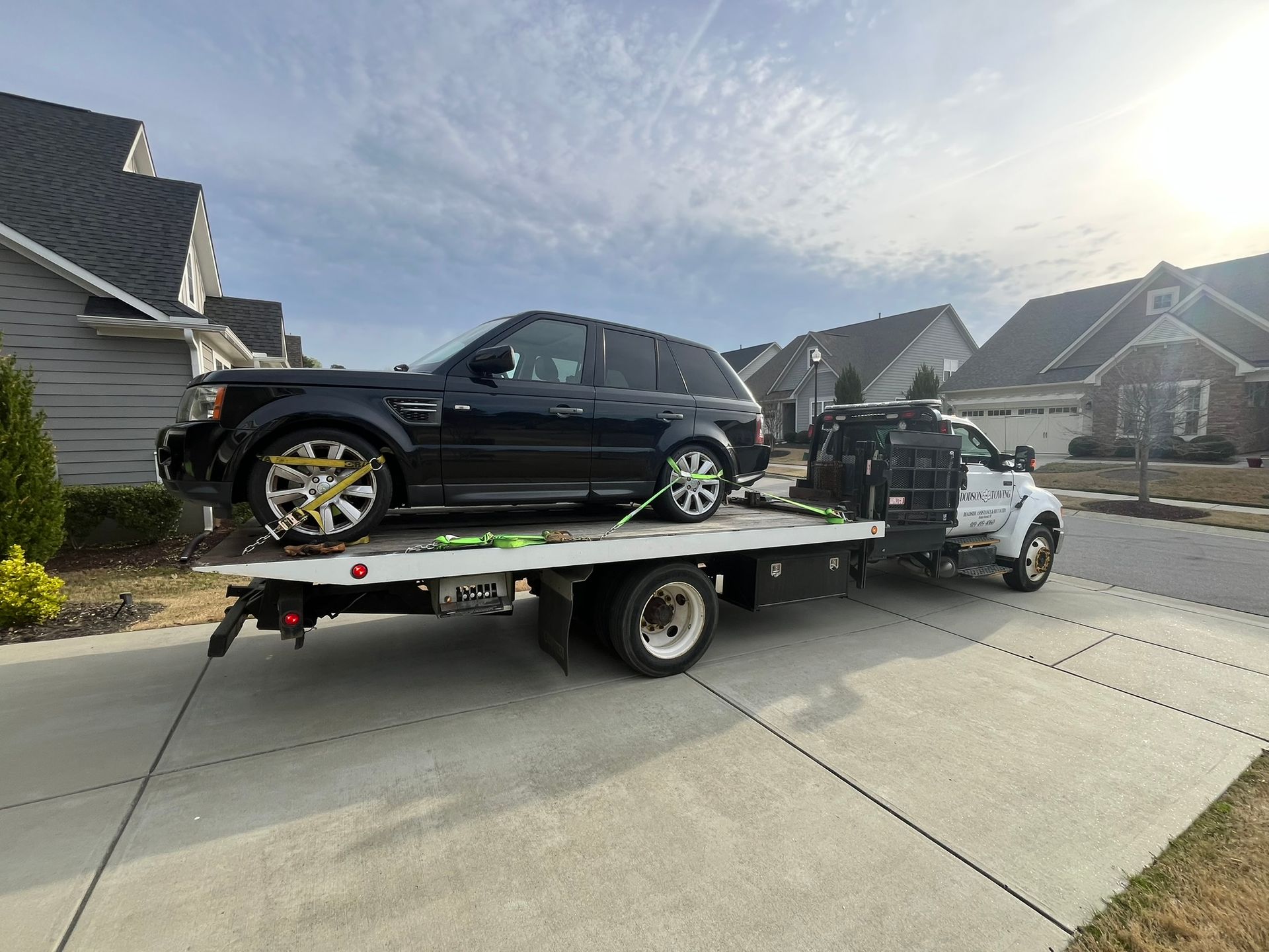 A black range rover is being towed by a tow truck.
