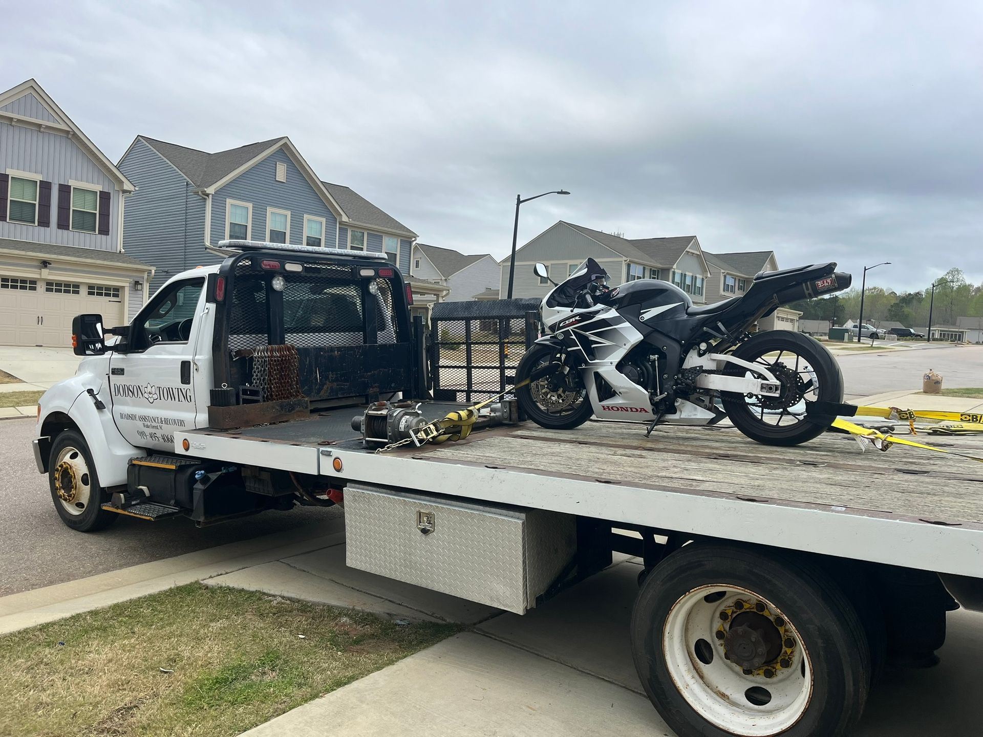 A motorcycle is sitting on the back of a tow truck.