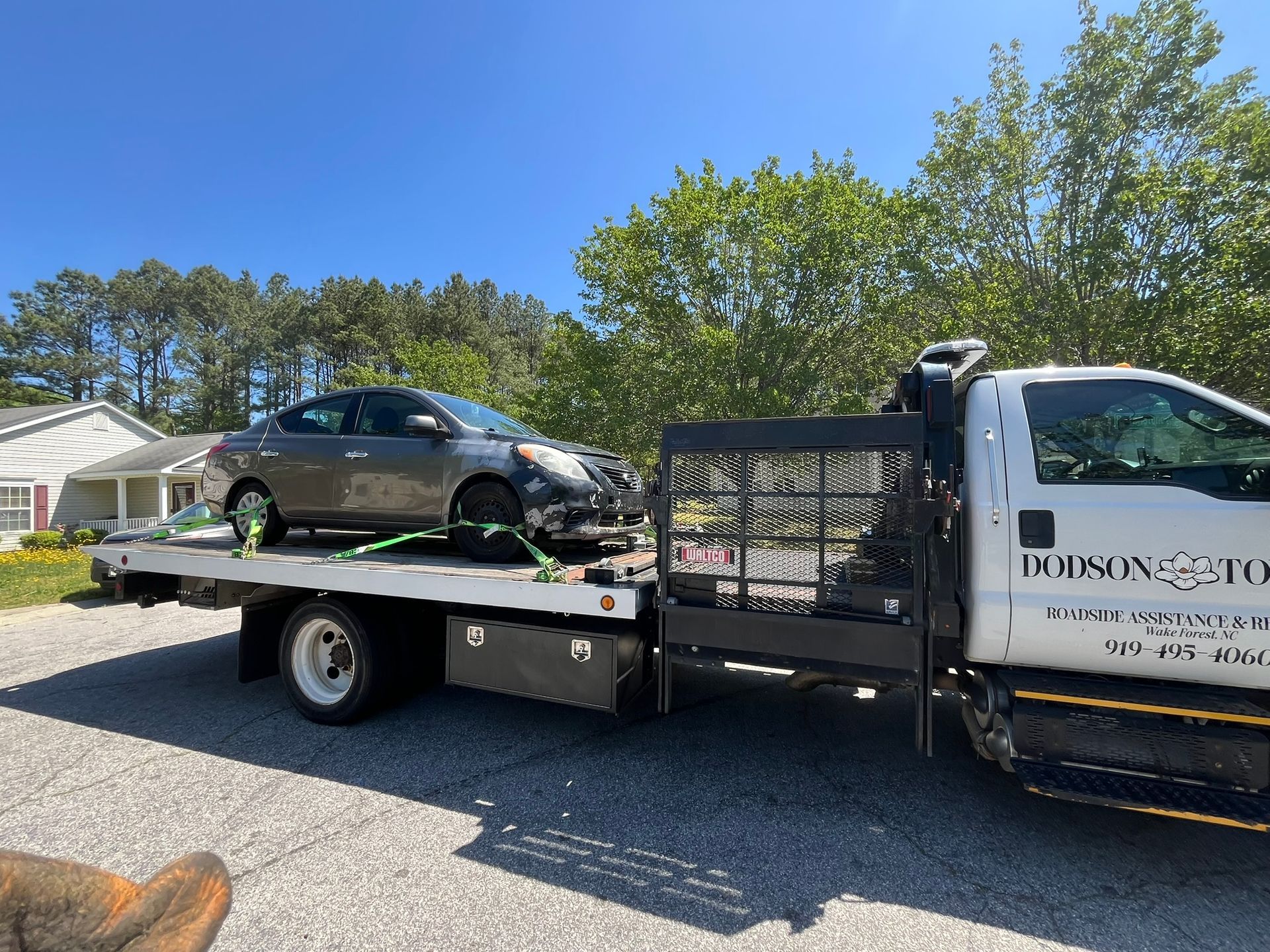 A tow truck is carrying a car on the back of it.