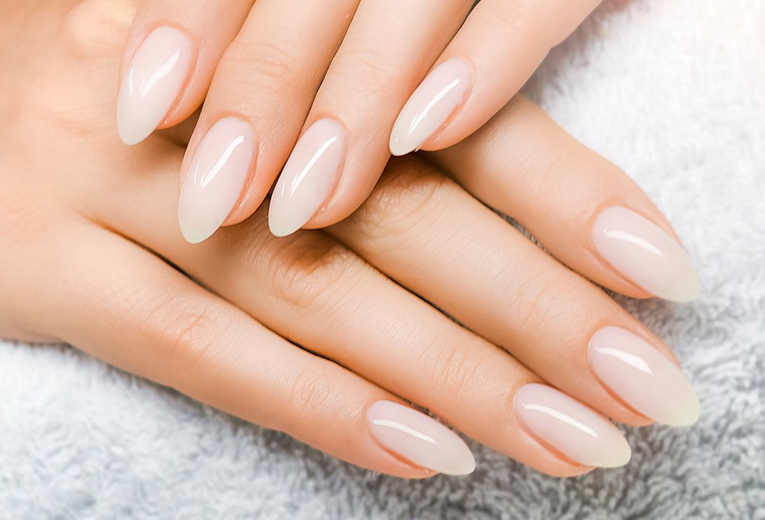 Woman's face peering through a torn pink paper, with red and patterned long nails.