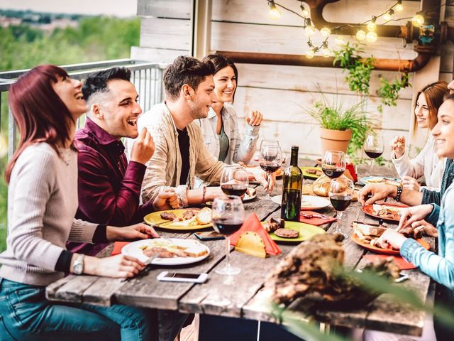 A group of people are sitting at a table eating food and drinking wine.