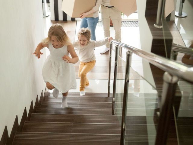 A family is moving into a new home and two children are running down the stairs.