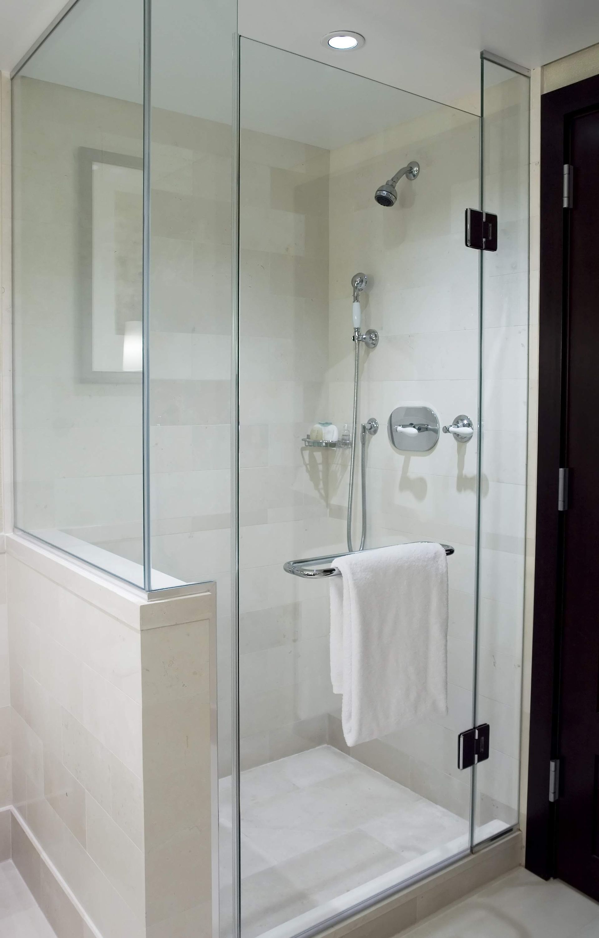 A bathroom with a walk in shower with a glass door