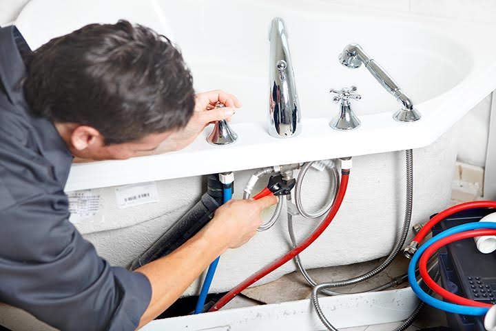 A man is fixing a bathroom sink with a wrench.