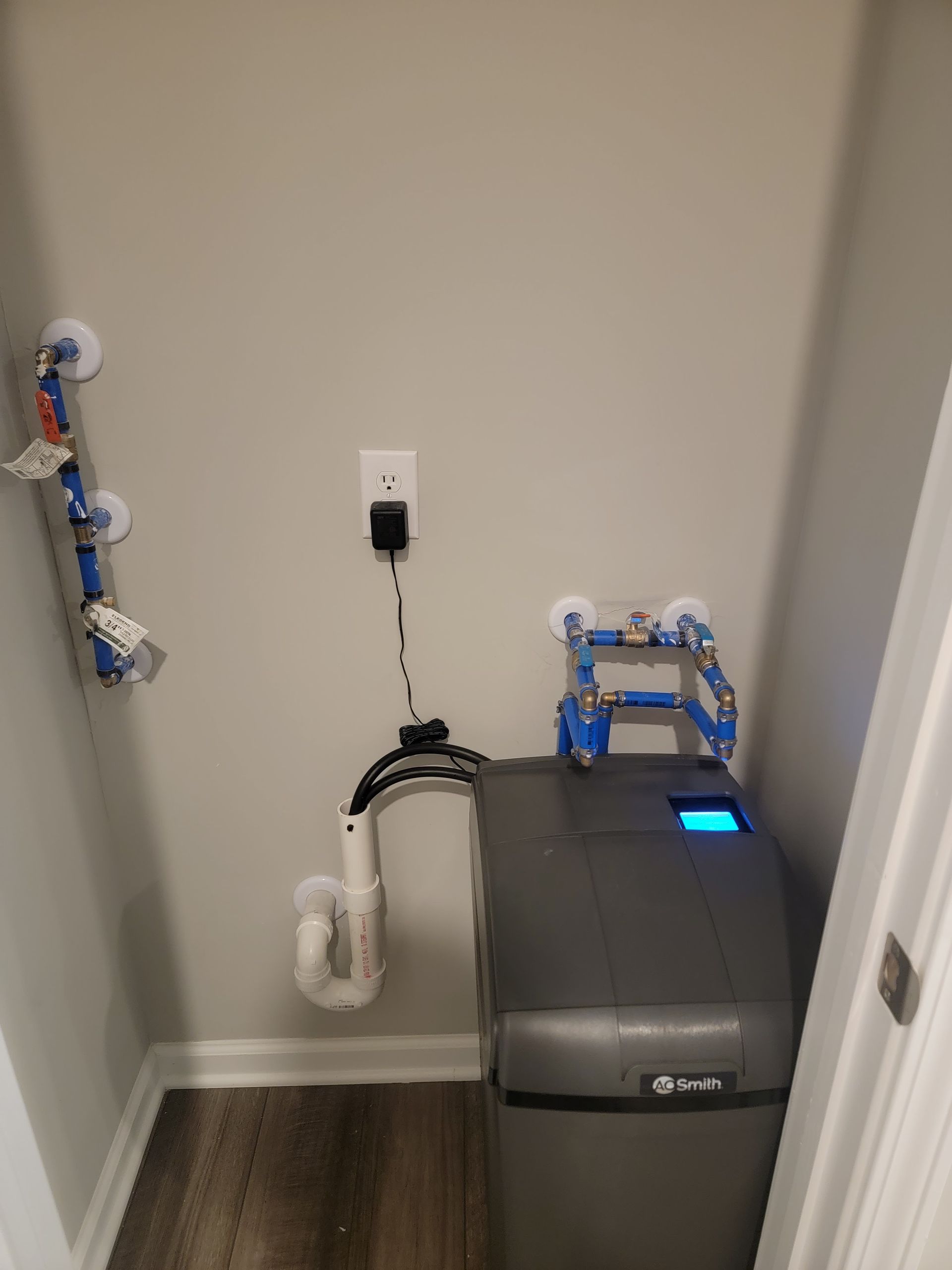 A water softener is sitting in a closet next to a sink.
