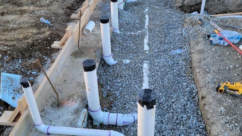 A bunch of pipes are sitting on top of a gravel road.