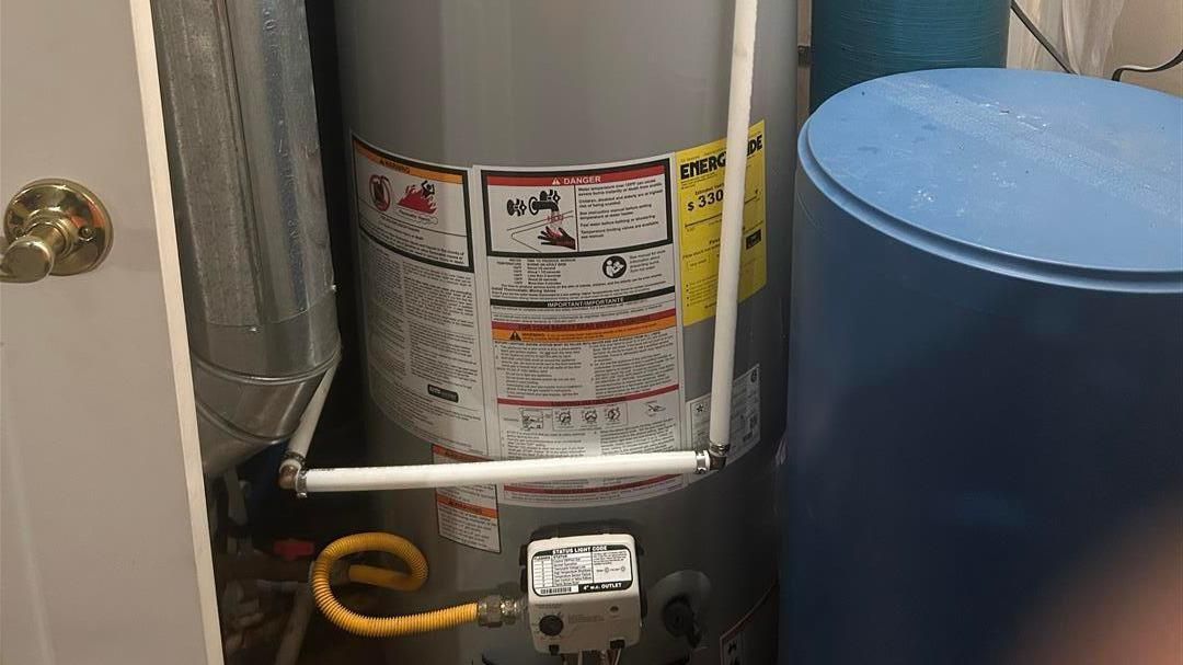 A gas water heater is sitting in a closet next to a blue tank.