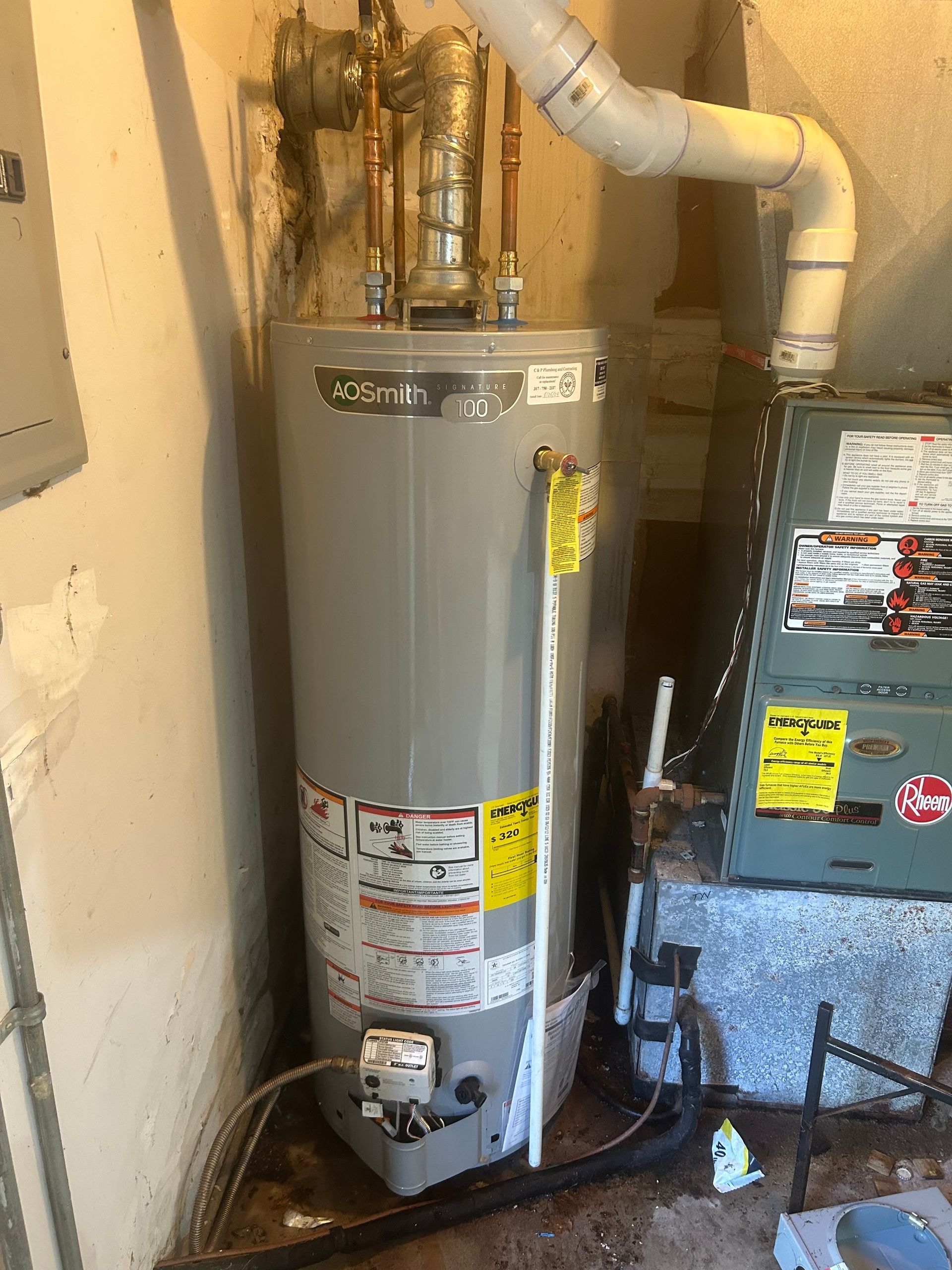 A water heater is sitting next to an air conditioner in a basement.