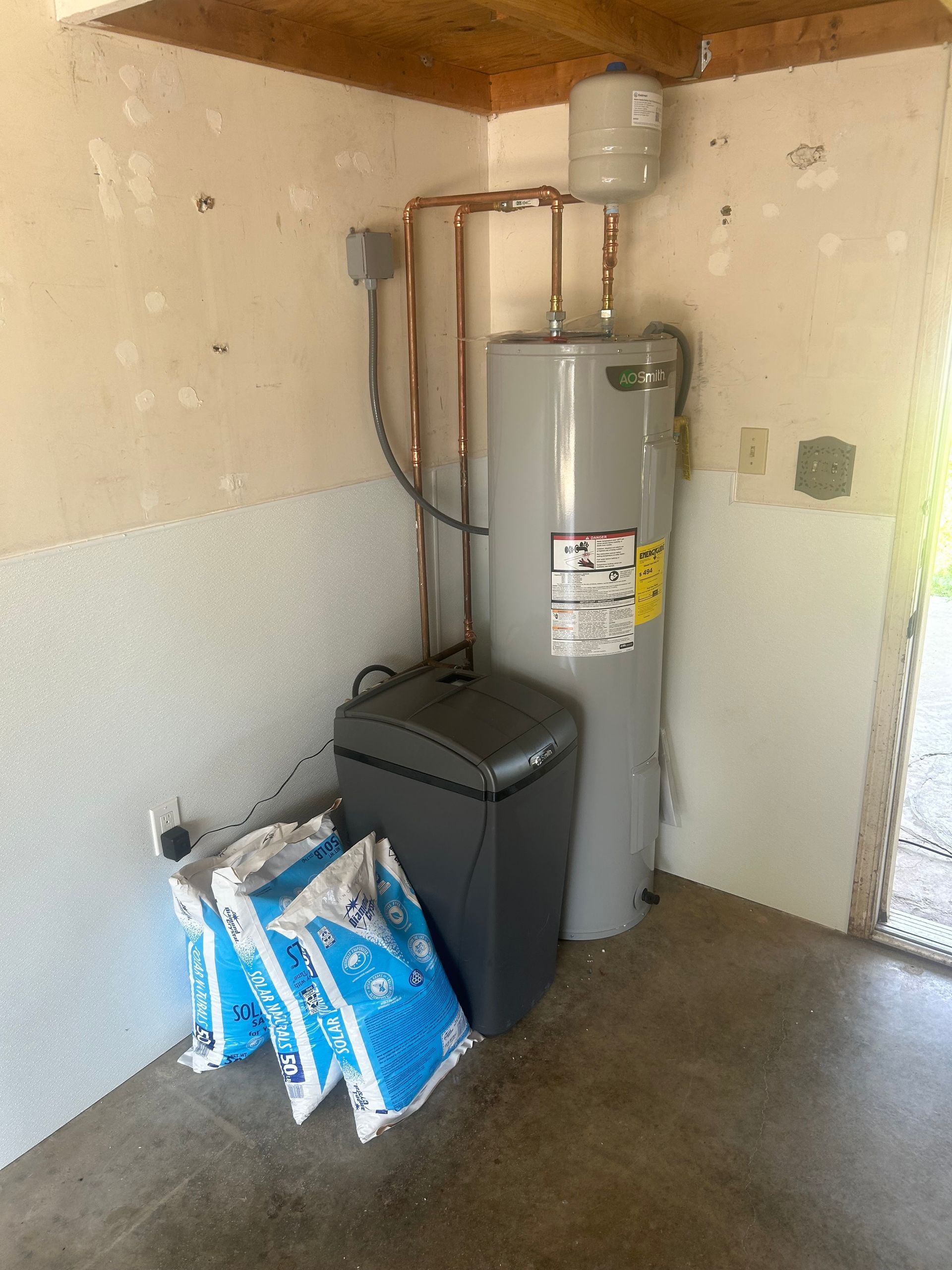 A room with a water heater and a washer and dryer.