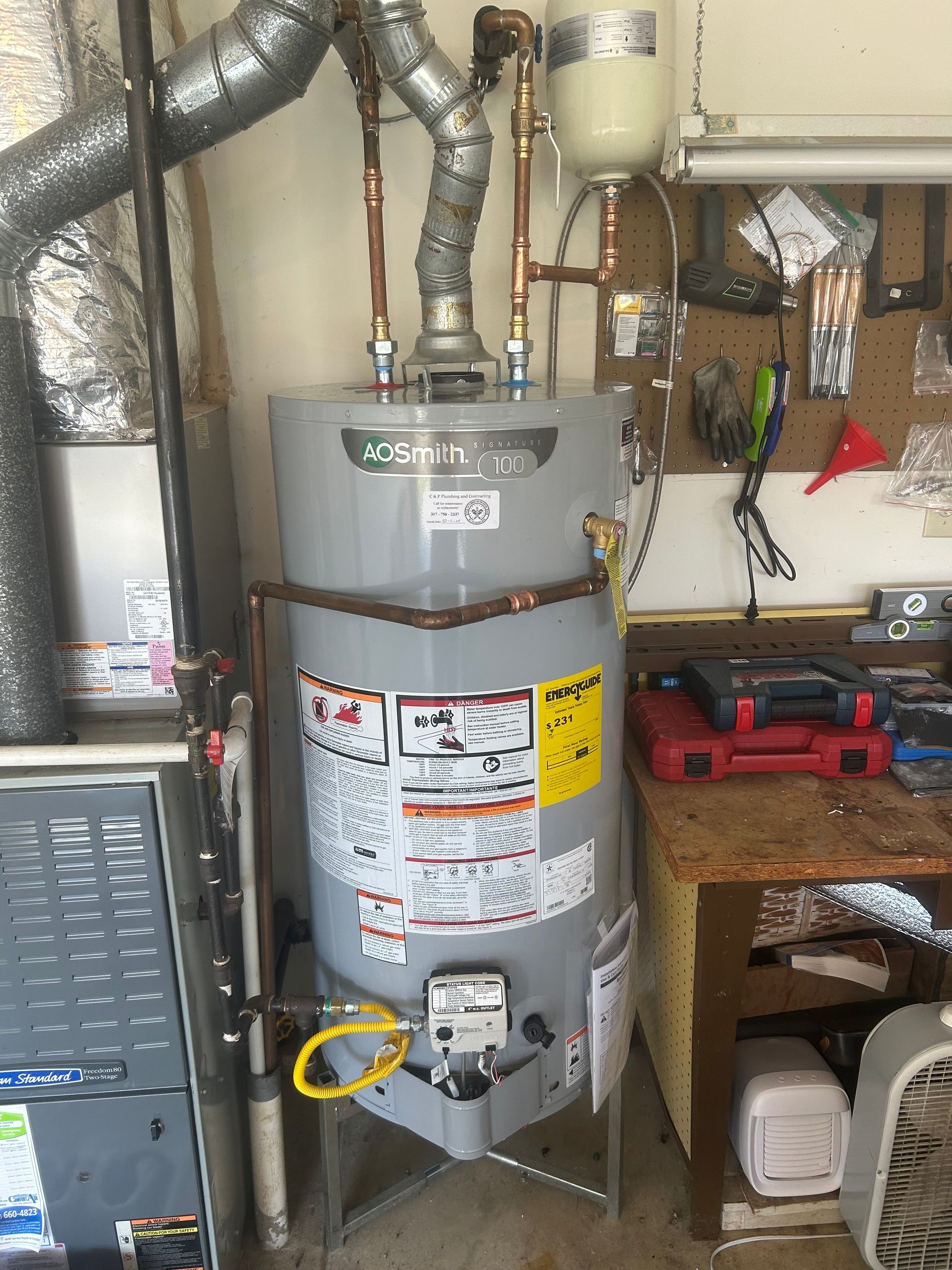 A water heater is sitting in a room next to a furnace.