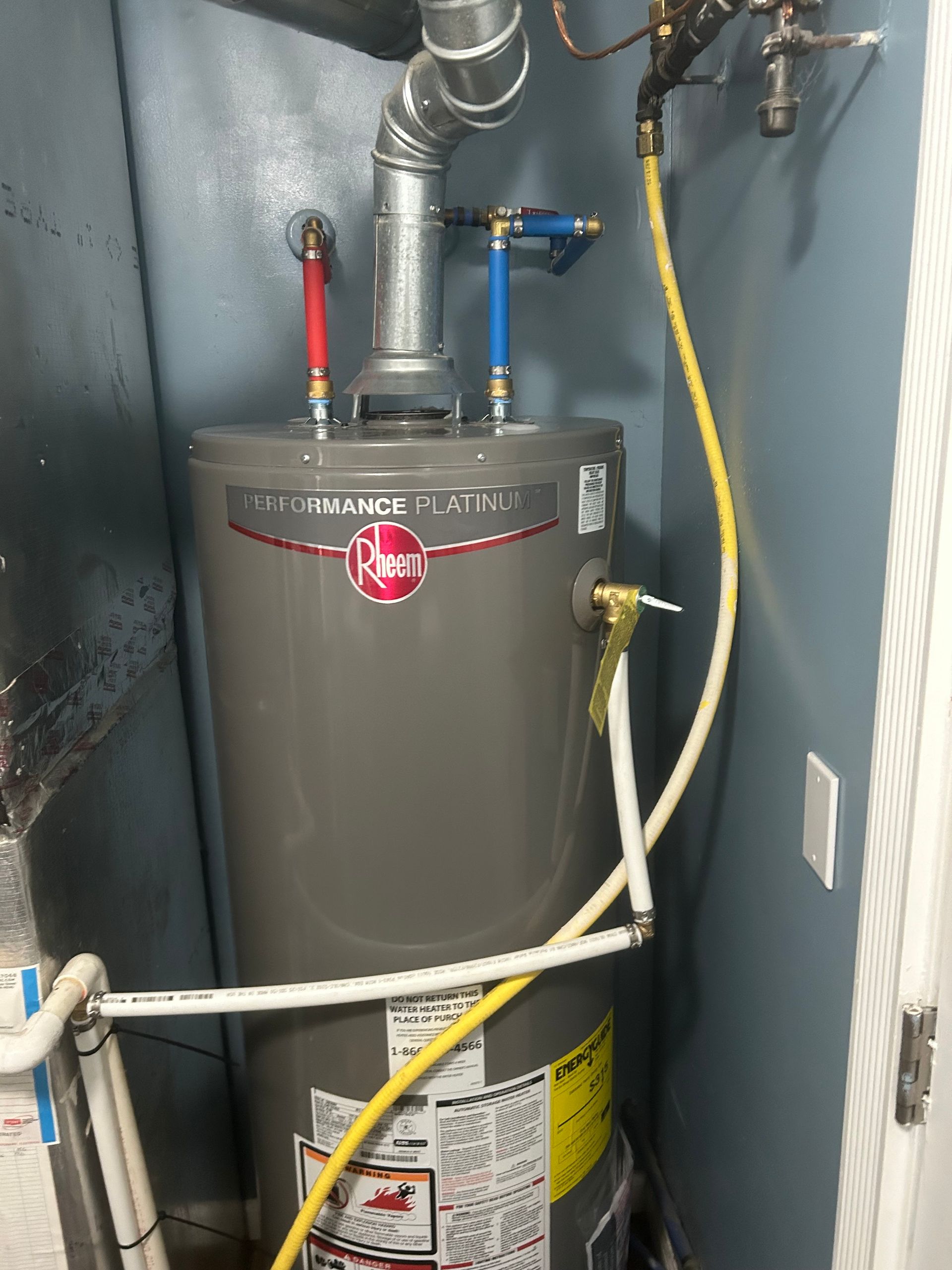 A gray water heater is sitting in a corner of a room.