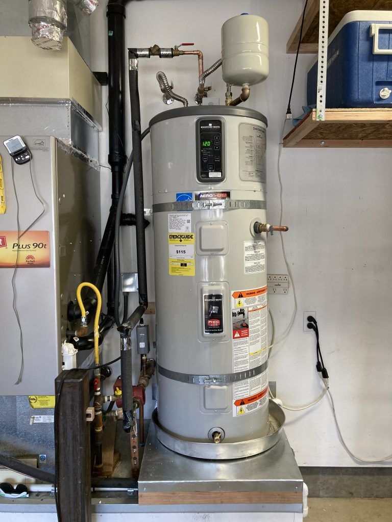 A water heater is sitting in a room next to a furnace.