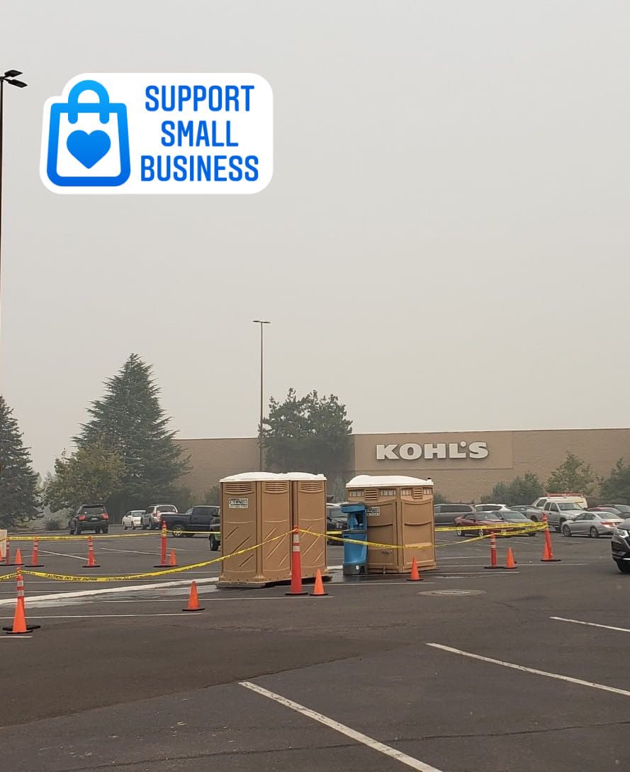 Two large boxes and two portable toilets in a Kohl's parking lot with a 