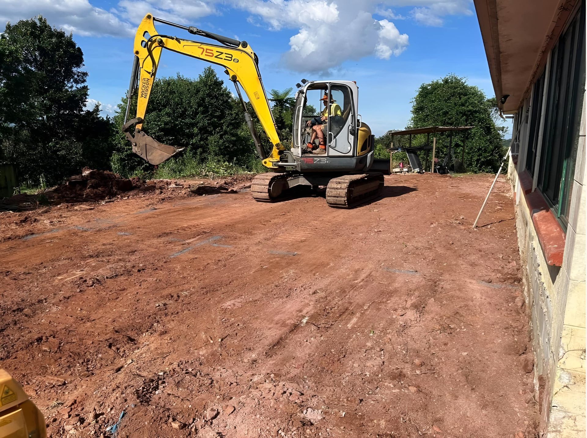 A Yellow Excavator Is Driving On A Dirt Road — Eclipse Hire In Edmonton, QLD