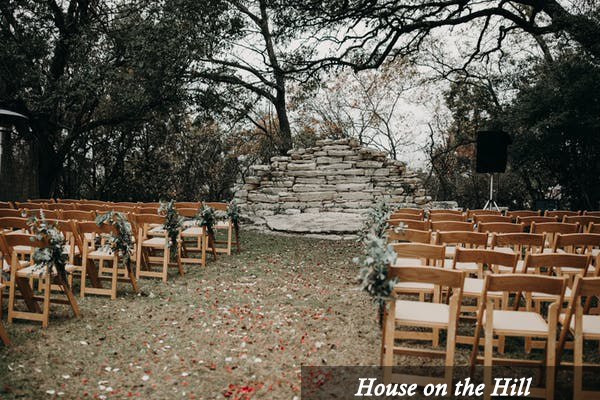 A row of wooden chairs are set up for a wedding ceremony at house on the hill