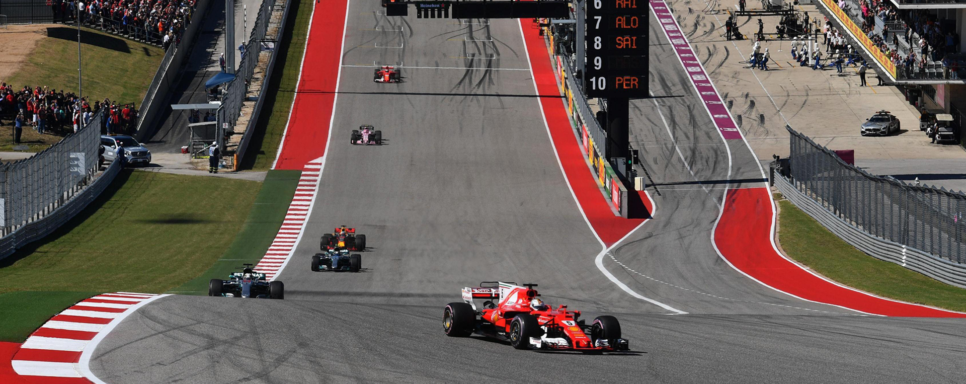 A race car is driving down a race track with a crowd watching