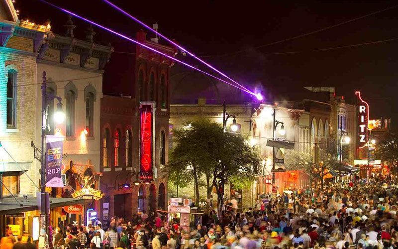 A crowd of people are gathered on a city street at night.