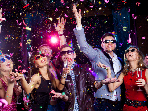 A group of people are having a party and throwing confetti in the air.