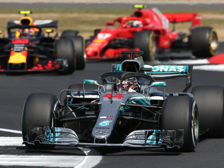 A group of race cars are driving down a track.