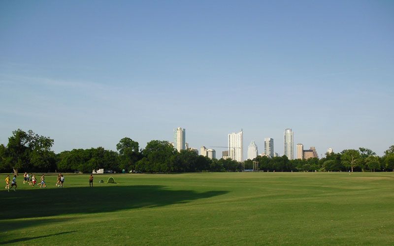 A large grassy field with a city skyline in the background