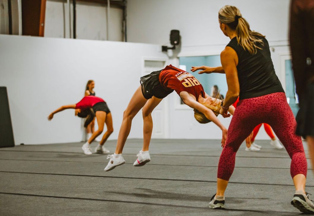 A group of cheerleaders are practicing their moves in a gym.