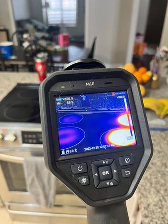 Thermal camera showing hot stove burners as orange-yellow circles.