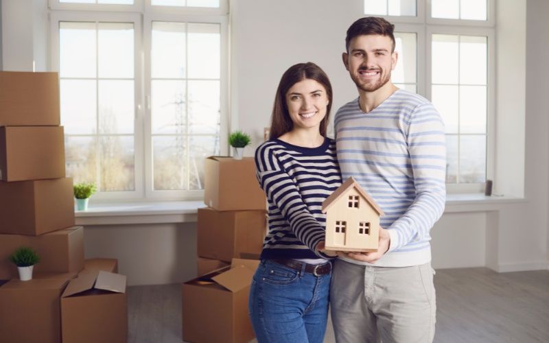A couple holding a model house in their home highlights the importance of paying a mortgage early.