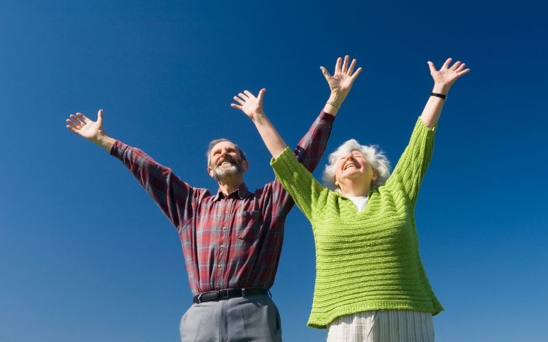 Seniors with their arms in the air as a sign of Debt Forgiveness and Stability in Retirement