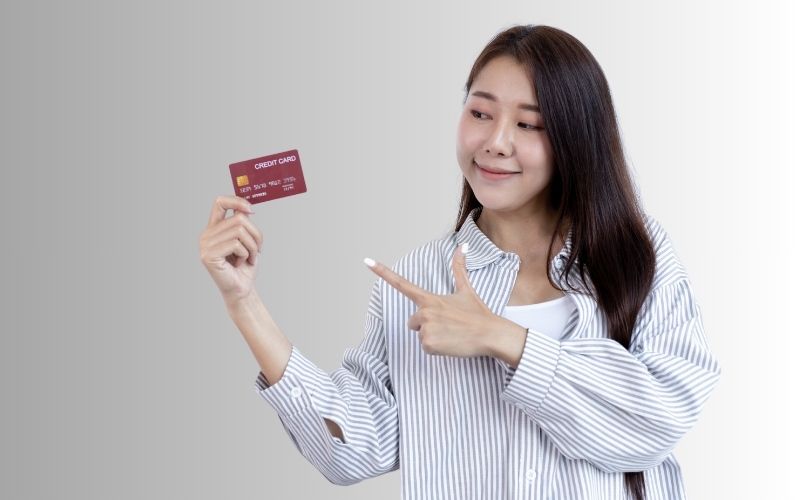  A woman holding a credit card emphasizes the idea of What Happens If You Stop Paying Credit Card?