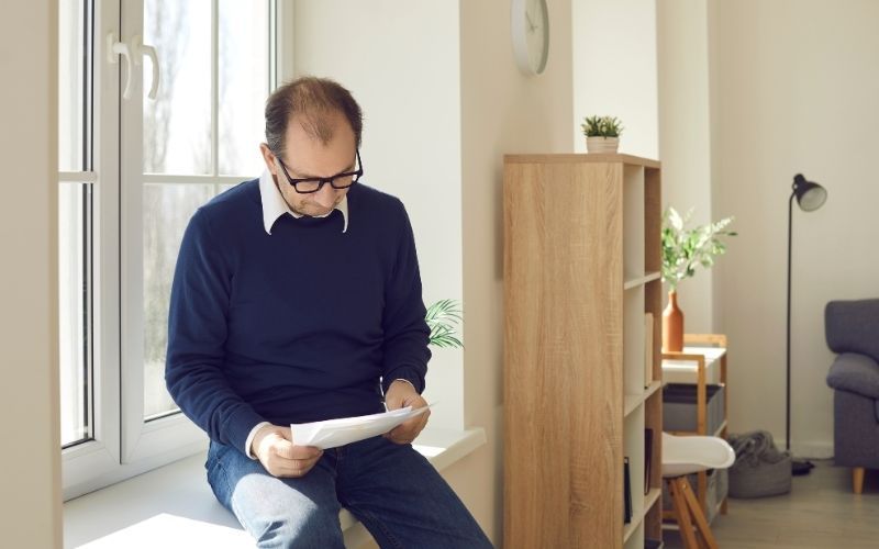 Man reviewing legal documents at home after being served with a debt collection lawsuit