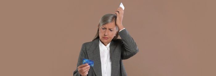 A woman is holding a credit card figuring out on how she will overcome the Debt Addiction 