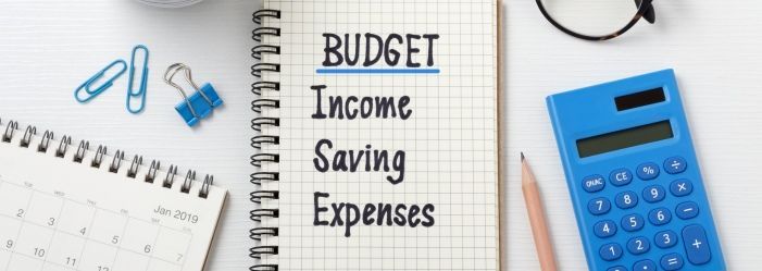 An image of a calculator, calendar, and notebook with the words budget, income, saving, and expenses written on it symbolizes Budgeting and Frugality