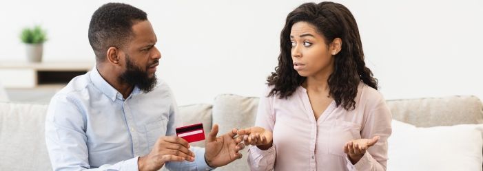 A man is holding a credit card and talking to a woman asking for what are the impacts Late Credit Card Payments