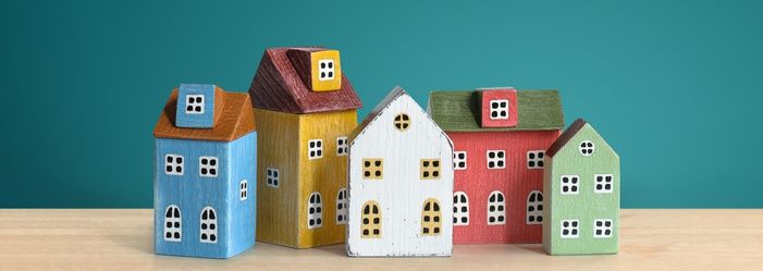 A group of small houses on top of a wooden table emphasizing how to pay off your mortgage early.