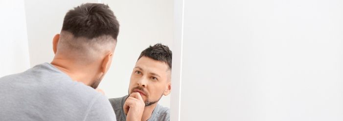 Image of a man standing in front of a mirror, reflecting deeply, symbolizing self-inquiry with a visual metaphor for the '10 Questions to Ask Yourself Before Making a Large Purchase'.