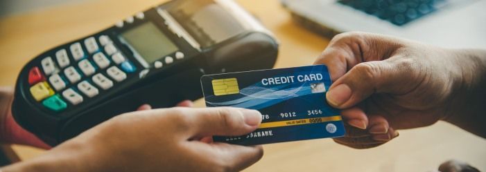 A person is holding a credit card in front of a credit card machine emphasizing the idea of Learning How to Rebuild Your Financial Life if you Stop Paying Credit card