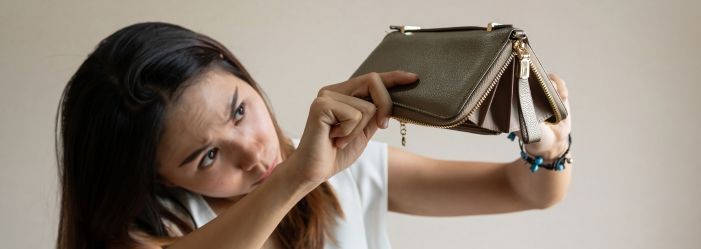 Frowning girl holds her upside down wallet over hand. Showing the wallet is empty due to debt ceiling's financial impact.