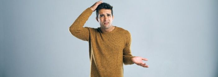 a man in a yellow sweater is scratching his head asking How To Choose The Right Debt Relief Option?