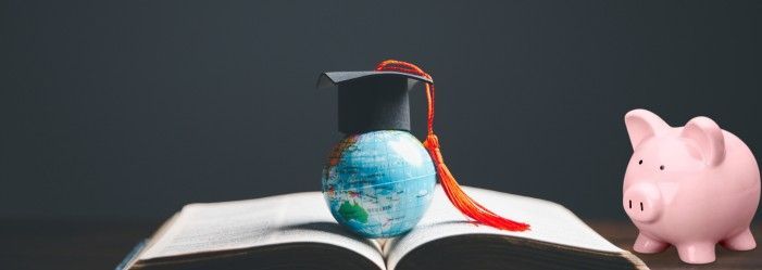A visual representation of post-grad financial planning. A globe sits atop a book, symbolizing global education, while a graduation cap signifies completion of studies. A piggy bank on the side emphasizes the importance of savings and financial management after graduation.