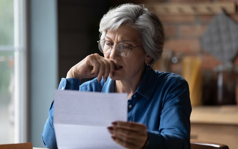 A woman looking at a piece of paper, considering how being a cosigner might affect her credit.