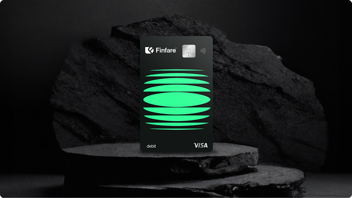 Black credit card with green design, displayed on a dark surface and against a dark background.