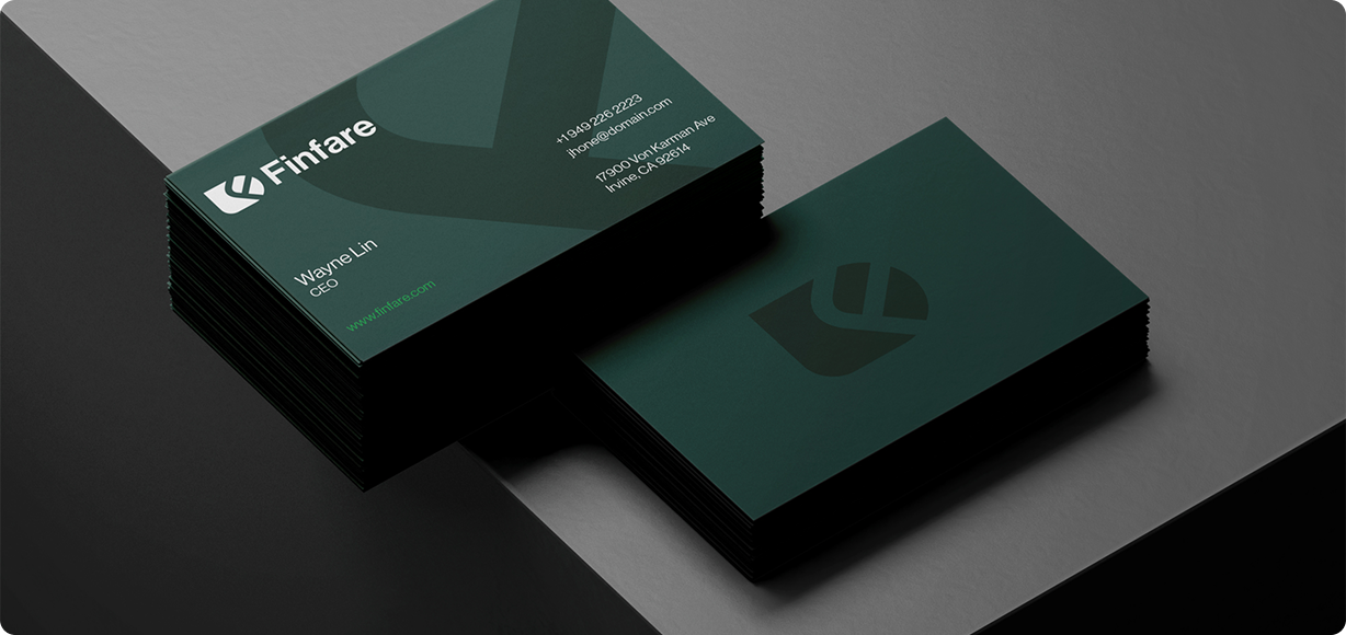 Business cards stacked and displayed on dark grey and black surfaces. Dark teal cards with white text and logo.