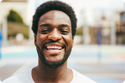 Man with a wide smile, in front of a colorful background.