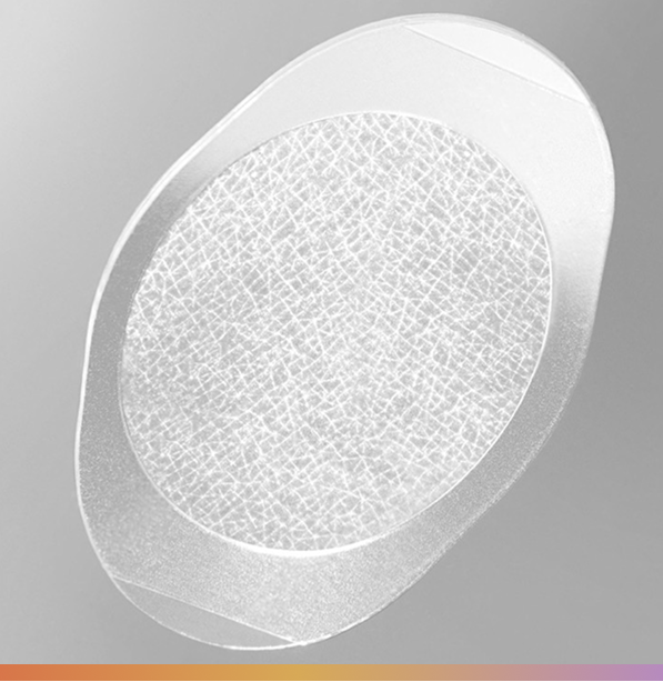 Oval-shaped, white medical wound dressing with central absorbent pad, and clear adhesive border.