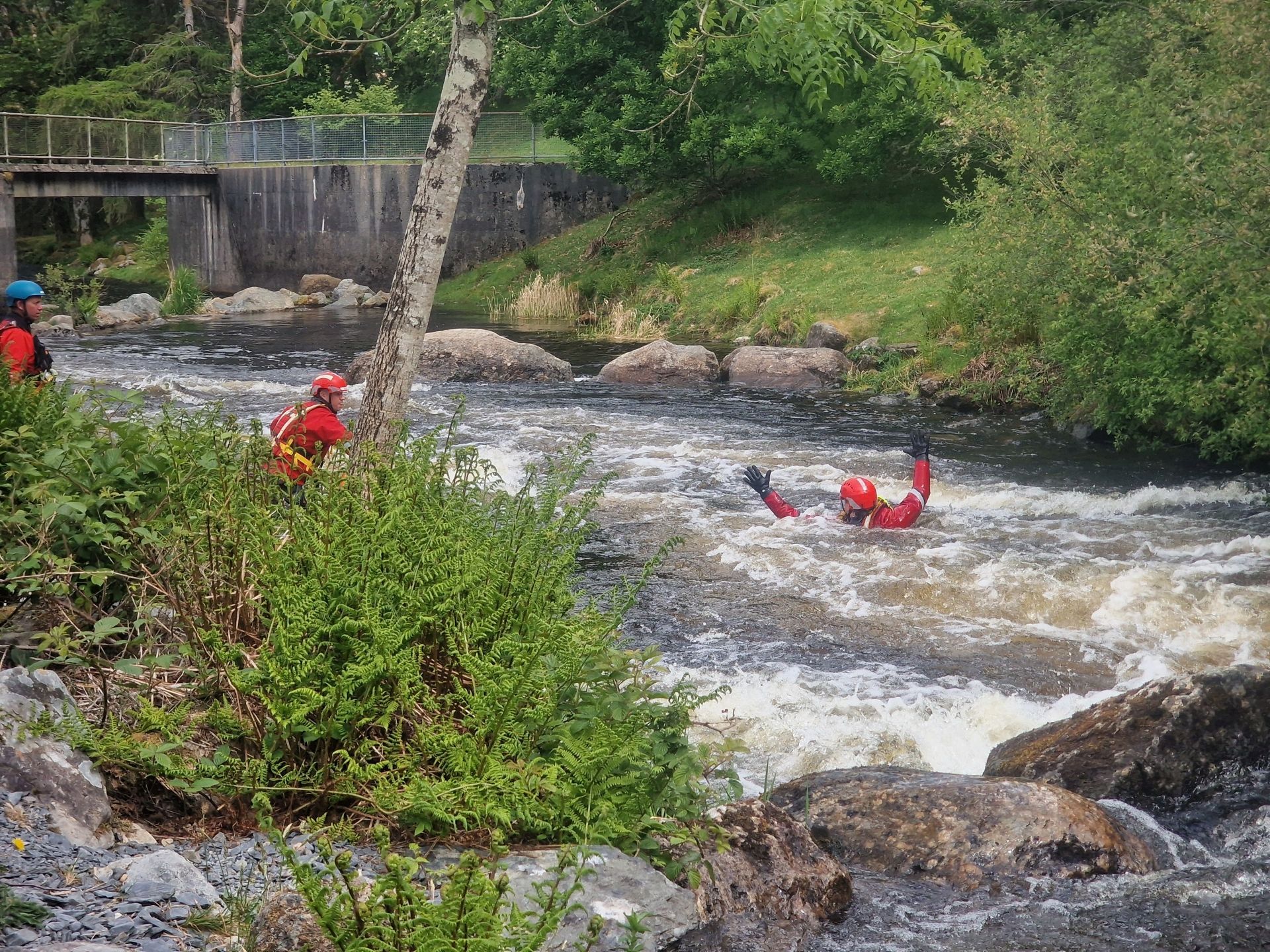 A rescuer throws a throwbag to their colleague, at Top Site, Canolfan Tryweryn