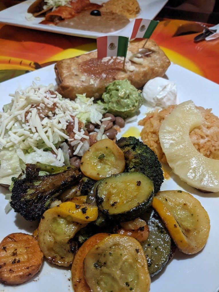 A white plate topped with a variety of mexican food on a table.
