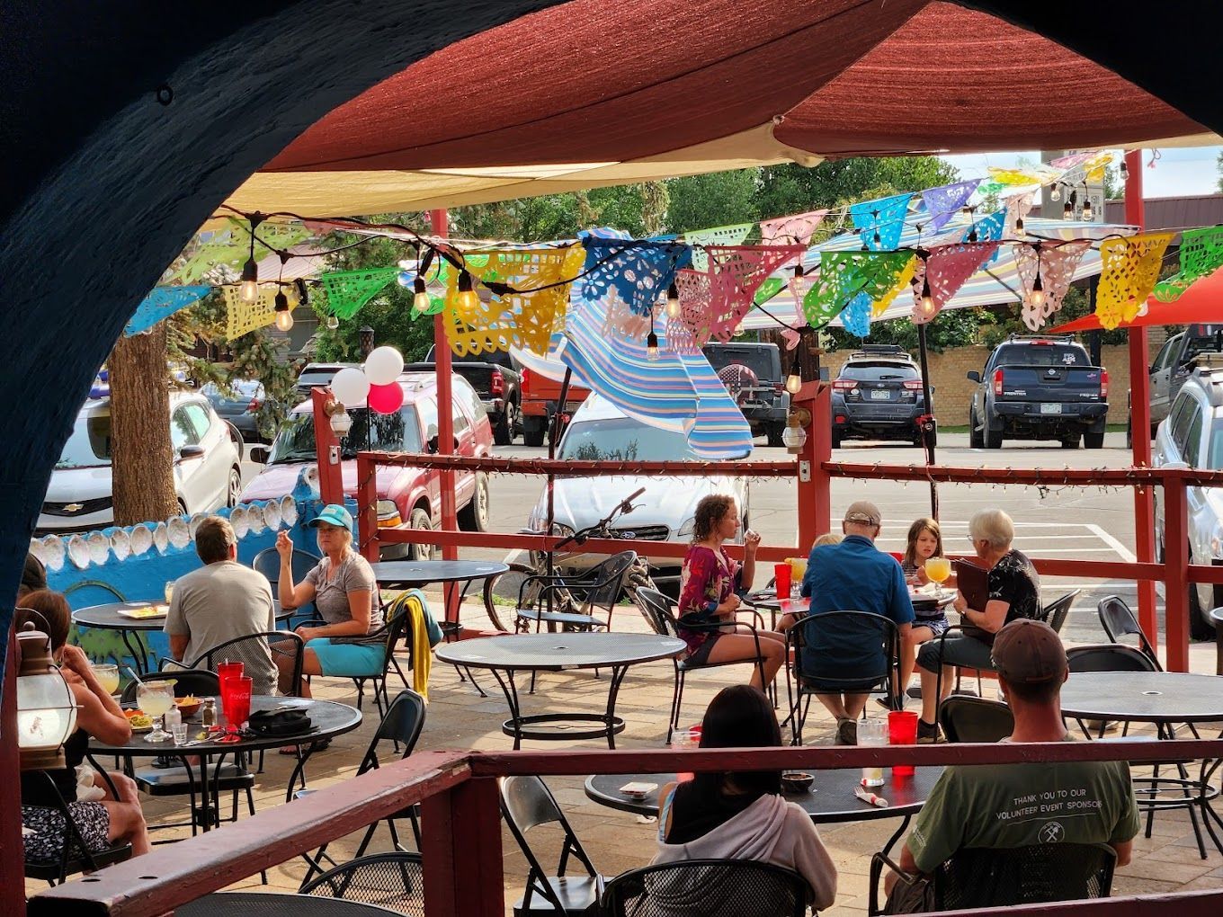 A group of people are sitting at tables outside of a restaurant.