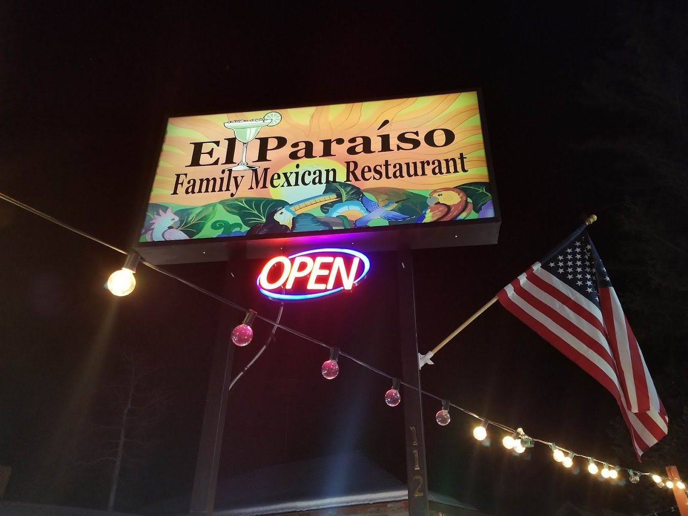 A sign for el paraiso family mexican restaurant is lit up at night